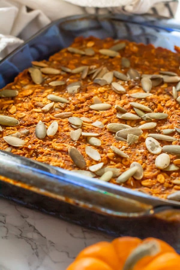 pumpkin baked oatmeal topped with pepitas in a blue square glass pyrex pan