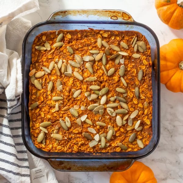 pumpkin baked oatmeal topped with pepitas in a blue square glass pyrex pan