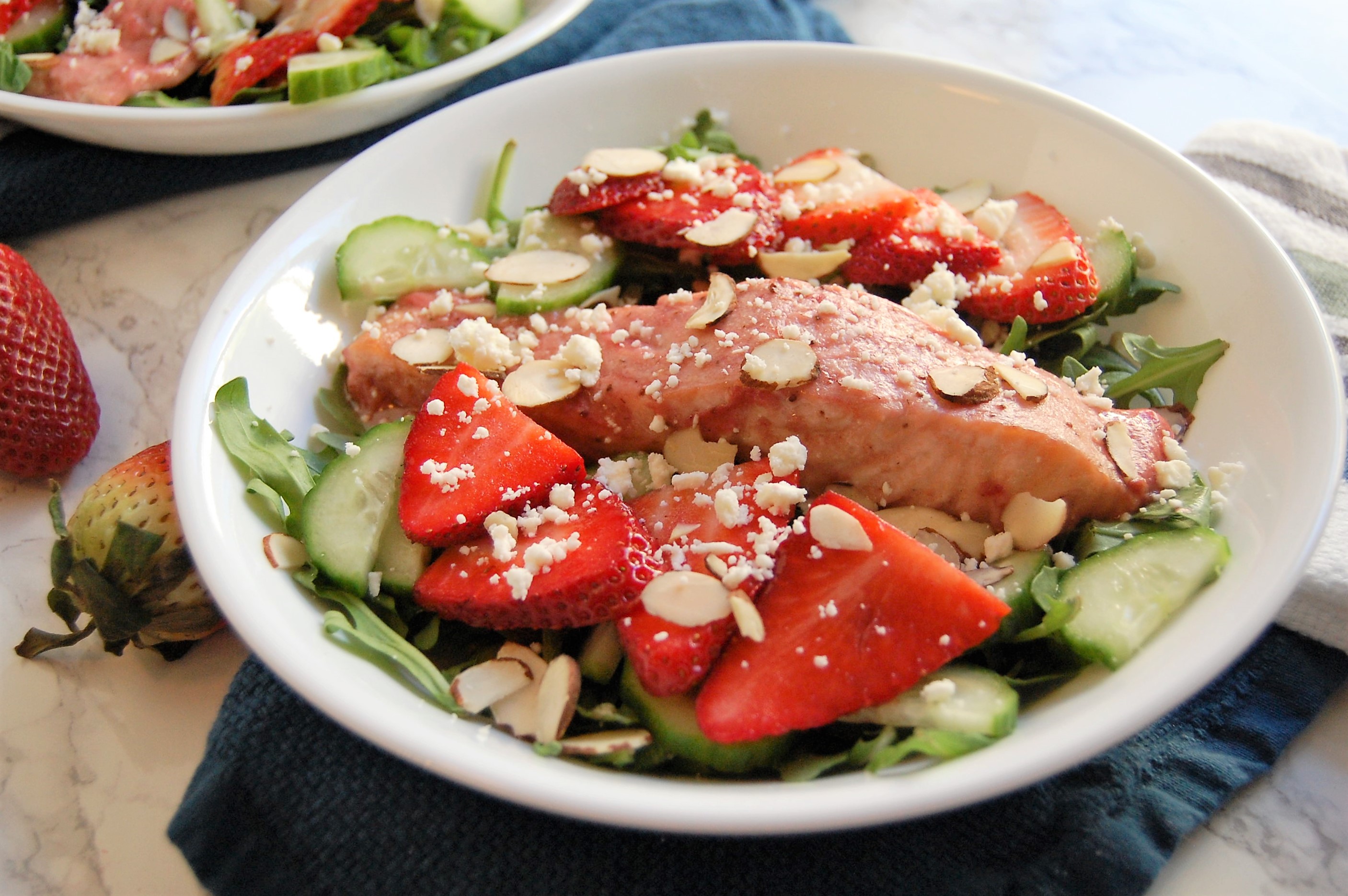 This fresh, springtime salad is a healthy entree salad with salmon baked in strawberry dressing. It has crisp cucumber toppings, sweet strawberries, crunchy almonds, creamy feta, and all served over a bed of spicy arugula. Try this easy, 30 minute dinner! | healthy recipe, salad recipe, salmon salad, strawberry salad, 30 minute meal, 30 minute dinner, pretty food, strawberries, strawberry salmon salad, dietitian recipe, nutritious recipe, healthy recipe |