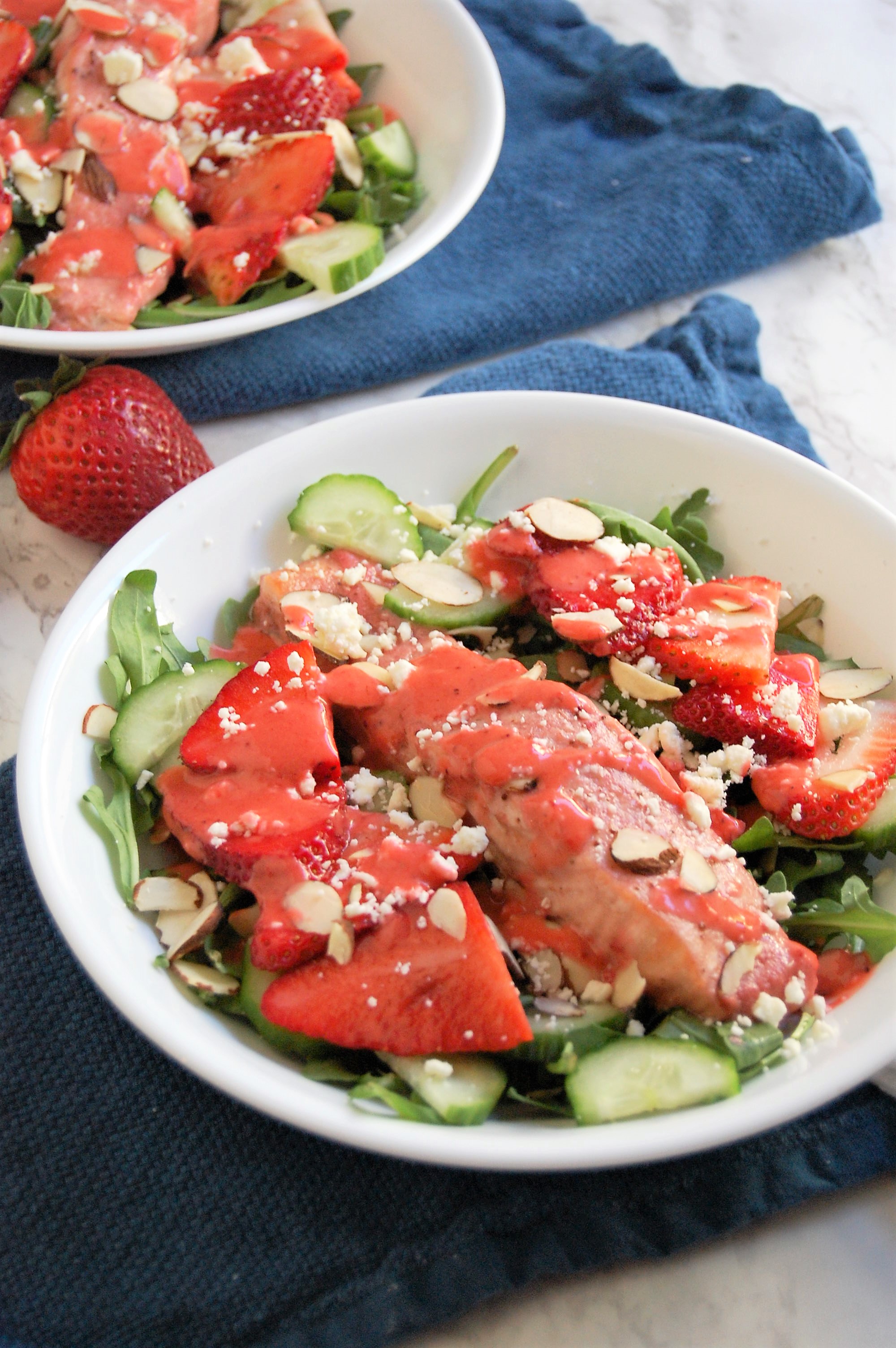 This fresh, springtime salad is a healthy entree salad with salmon baked in strawberry dressing. It has crisp cucumber toppings, sweet strawberries, crunchy almonds, creamy feta, and all served over a bed of spicy arugula. Try this easy, 30 minute dinner! | healthy recipe, salad recipe, salmon salad, strawberry salad, 30 minute meal, 30 minute dinner, pretty food, strawberries, strawberry salmon salad, dietitian recipe, nutritious recipe, healthy recipe |