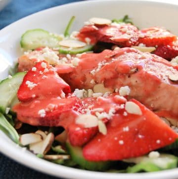 This fresh, springtime salad is a healthy entree salad with salmon baked in strawberry dressing. It has crisp cucumber toppings, sweet strawberries, crunchy almonds, creamy feta, and all served over a bed of spicy arugula. Try this easy, 30 minute dinner! | healthy recipe, salad recipe, salmon salad, strawberry salad, 30 minute meal, 30 minute dinner, pretty food, strawberries, strawberry salmon salad, dietitian recipe, nutritious recipe, healthy recipe |