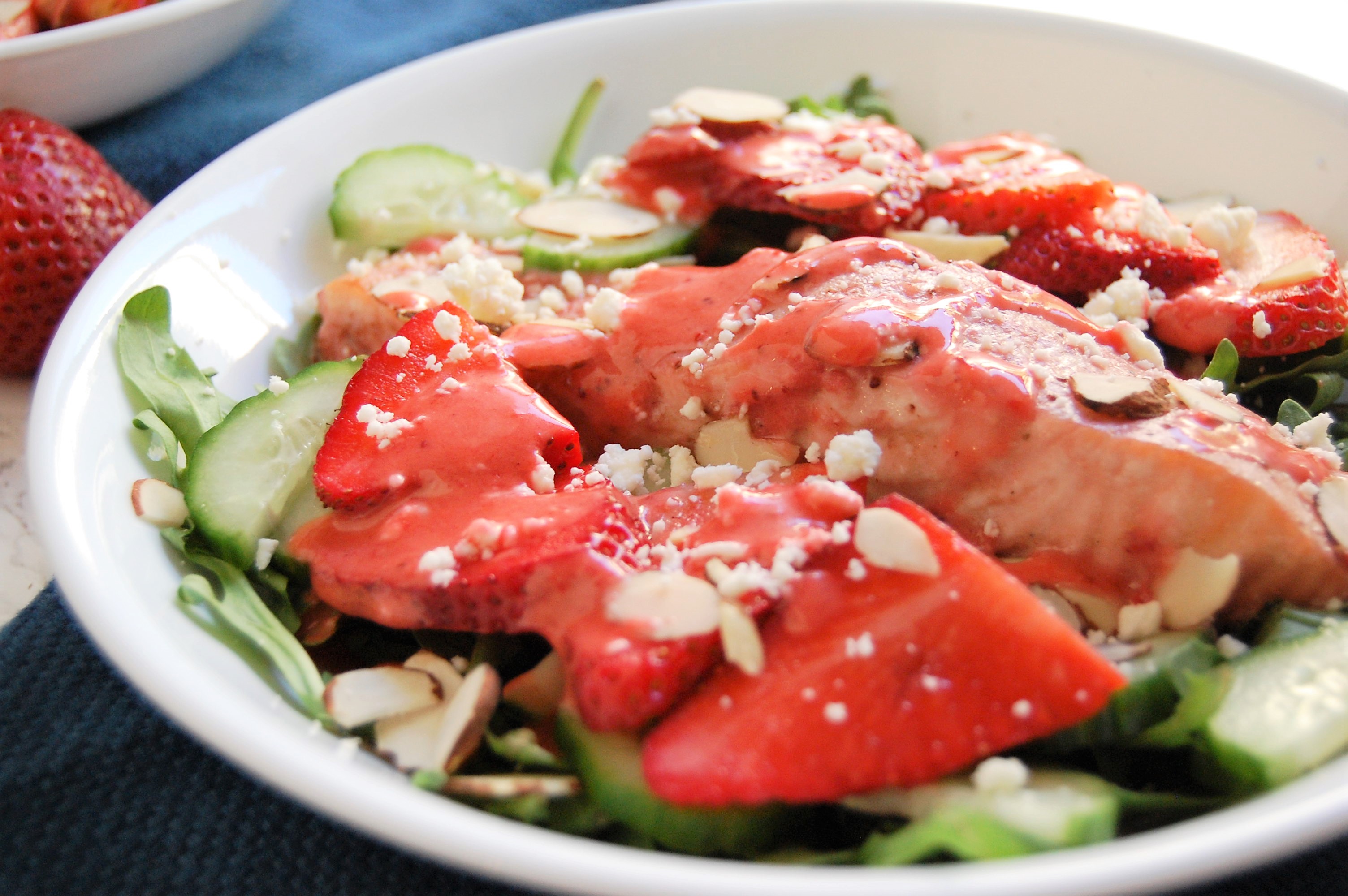 This fresh, springtime salad is a healthy entree salad with salmon baked in strawberry dressing. It has crisp cucumber toppings, sweet strawberries, crunchy almonds, creamy feta, and all served over a bed of spicy arugula. Try this easy, 30 minute dinner! | healthy recipe, salad recipe, salmon salad, strawberry salad, 30 minute meal, 30 minute dinner, pretty food, strawberries, strawberry salmon salad, dietitian recipe, nutritious recipe, healthy recipe |