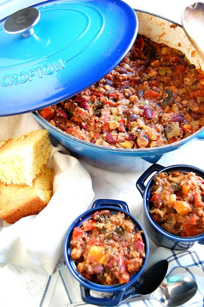 Hearty Vegetable Chili in a blue dutch oven with cornbread.