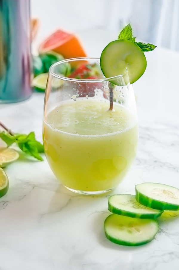 Stemless wine glass of cucumber mint agua fresca with cucumber and mint garnish.