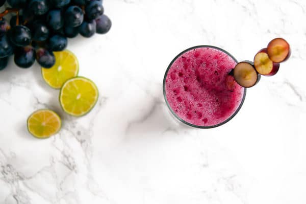 Overhead view of a bright purple froth on a glass of freshly blended grape agua fresca