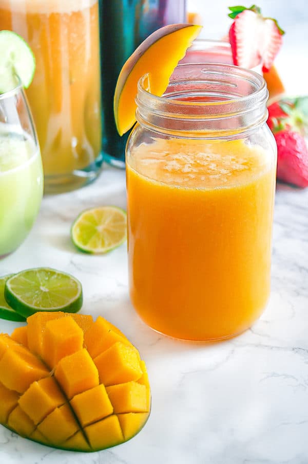 Mango Agua Fresca in a mason jar with fresh mango and lime garnish.