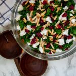 Overhead shot of winter kale salad with cranberries, goat cheese, toasted almonds, and a lightly sweet cranberry vinaigrette.