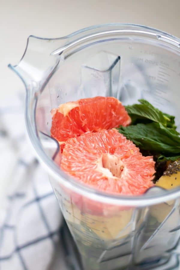 A vitamix blender full of grapefruit smoothie ingredients.