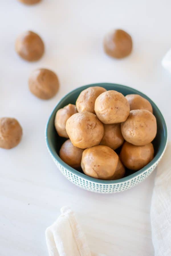 A small white bowl with teal accents holding no bake peanut butter energy balls.