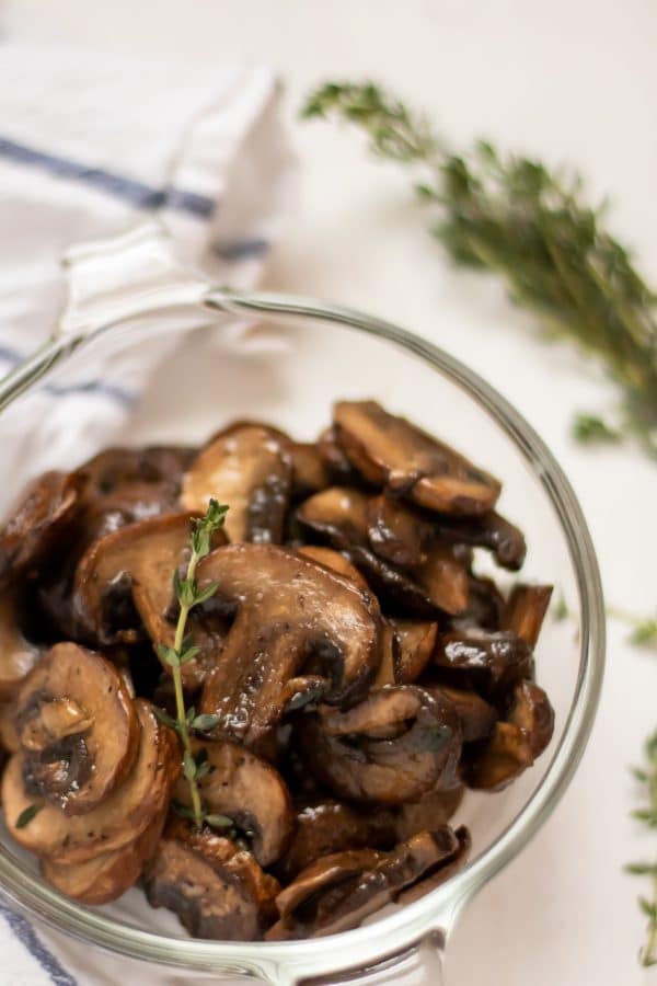 gezonde, gemakkelijk te bakken champignons in een glazen kom versierd met een takje tijm.