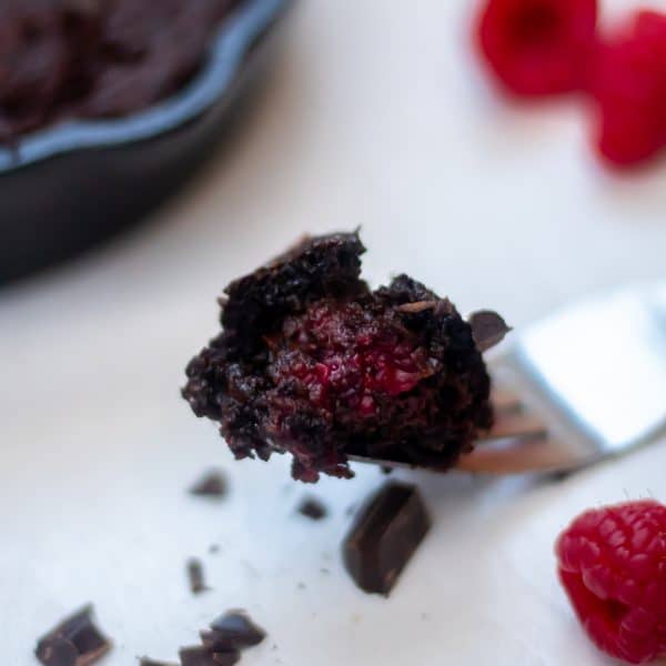 A fork with a bite of gluten-free grain-free skillet brownies with raspberries