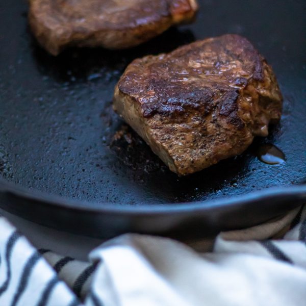 Close up of a seared sirloin steak in a cast iron skillet.