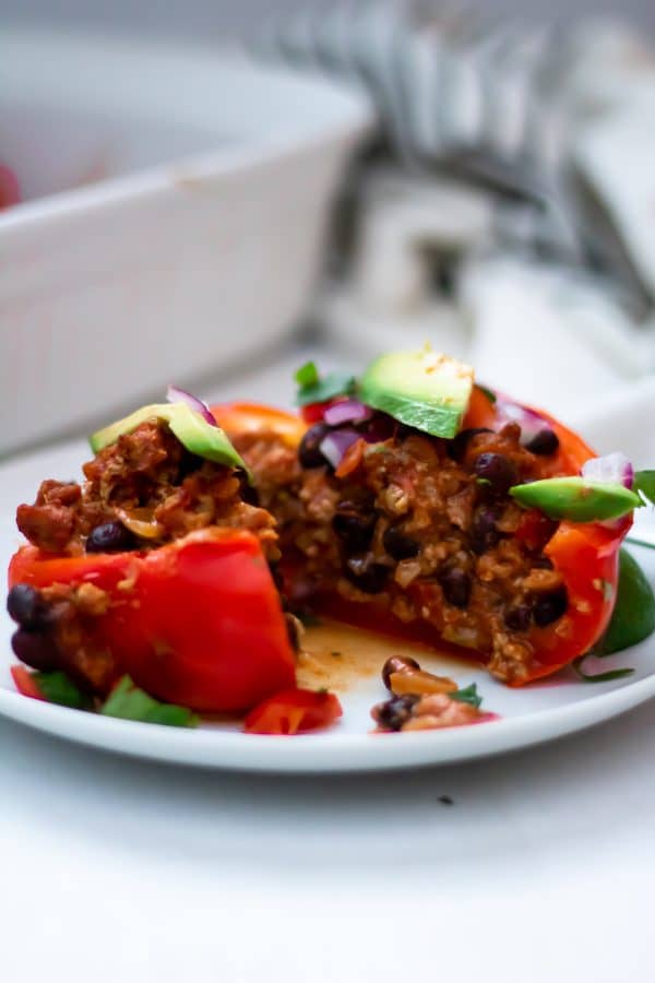 A taco stuffed pepper cut open to see a delicious cheesy filling of turkey, black beans, salsa, and cheese.