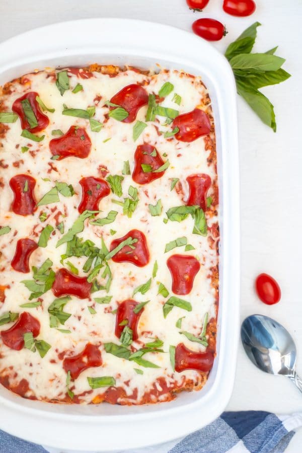 Overhead shot of a pizza quinoa casserole with turkey pepperoni, fresh basil, and melty cheesy topping.