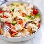 A fork in a bowl of honey mustard chicken salad.