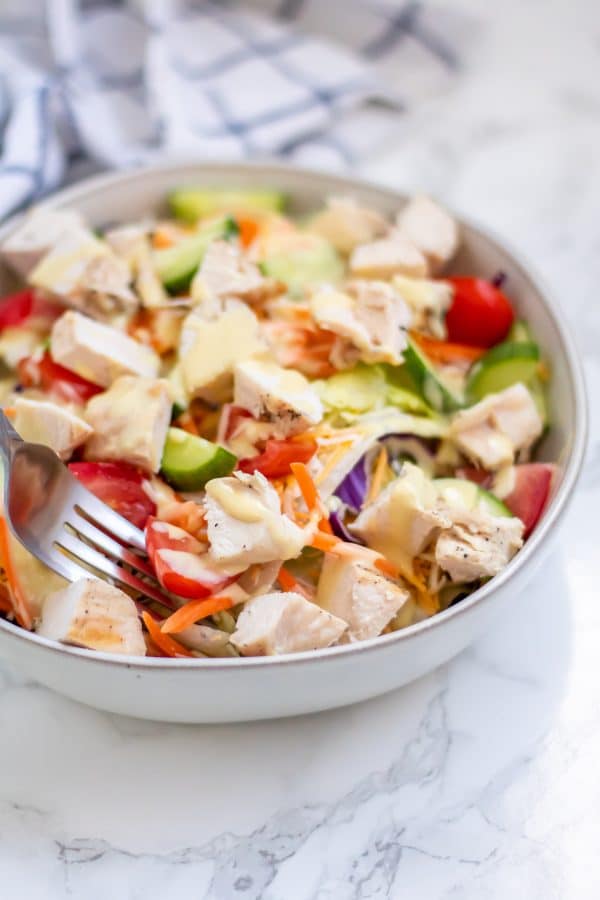 A fork in a bowl of honey mustard chicken salad.