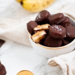 A small bowl filled with frozen banana bites with peanut butter and covered in chocolate.