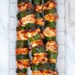 BBQ chicken skewers with zucchini on an ivory plate.