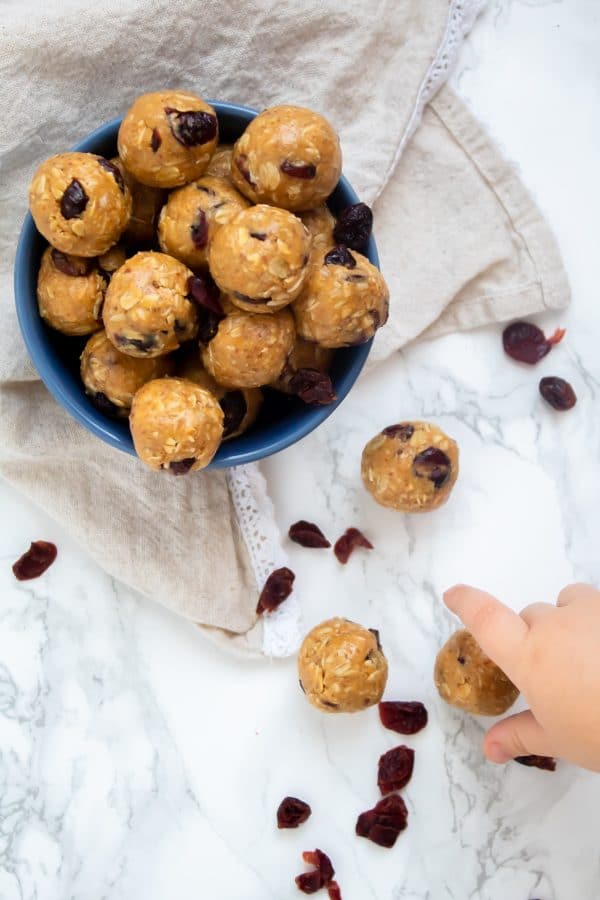 A bowl of Peanut Butter & Jelly Bites with a sneaky toddler hand stealing a bite.