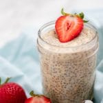 creamy pale tan overnight orange oats in a mason jar accented with halved strawberries