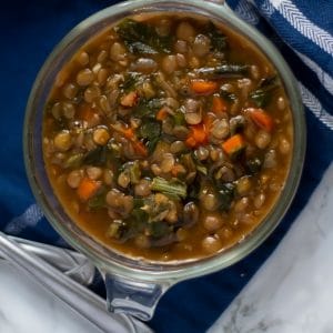 An overhead of a glass bowl filled with lentil stew with turnip greens