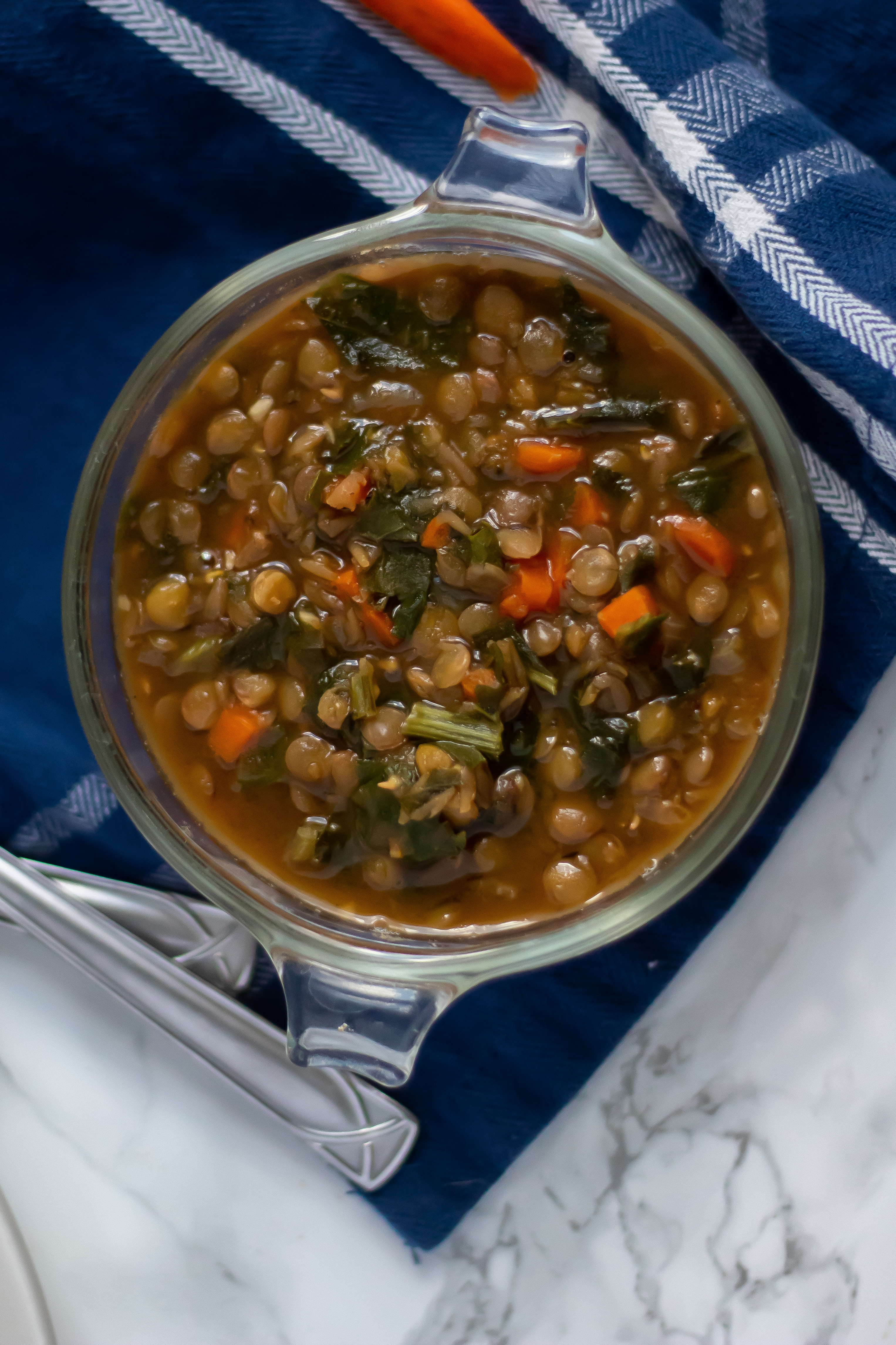 An overhead of a glass bowl filled with lentil stew with turnip greens