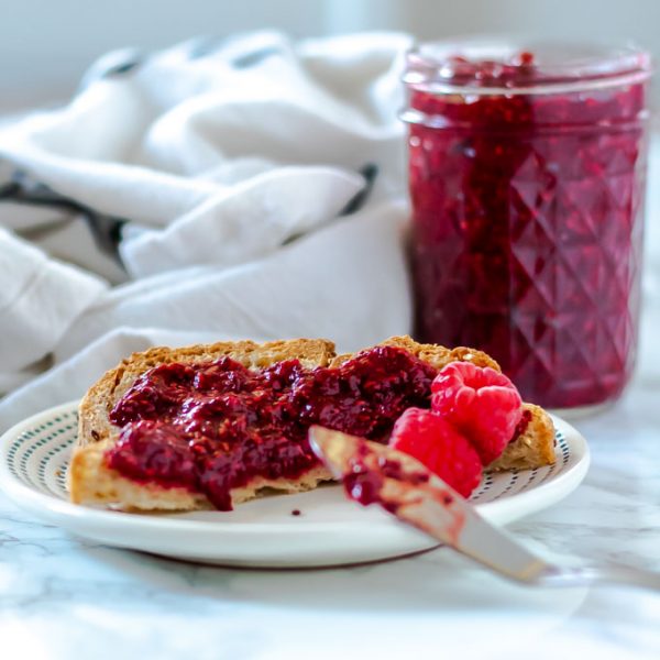 toast with raspberry jam with a mason jar of jam in the background