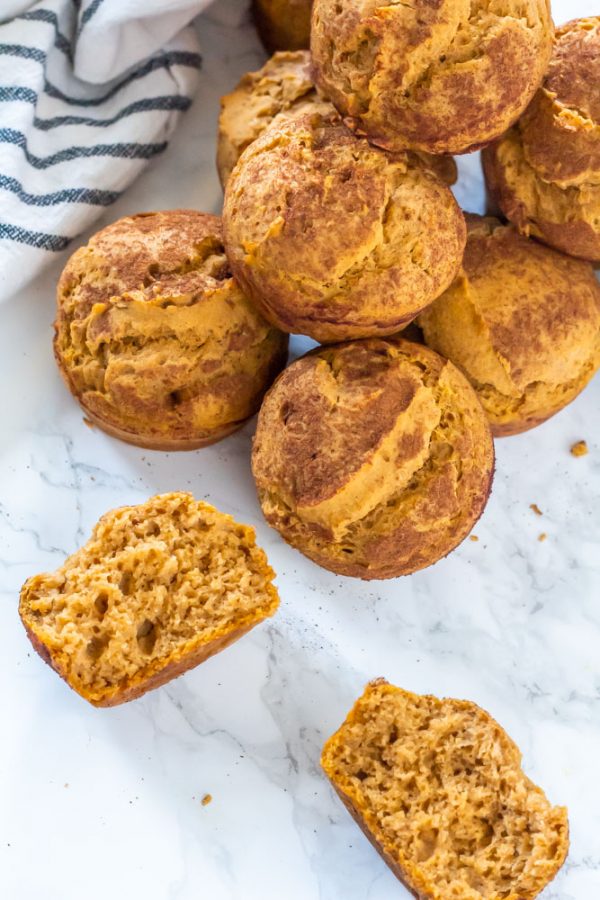 a pile of pumpkin muffins with one broken in half, facing up