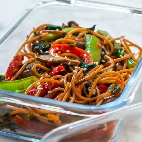 A glass meal prep container of lo mein with sesame seeds on top