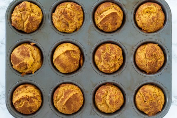 pumpkin muffins in a metal pan with cinnamon sprinkled on top