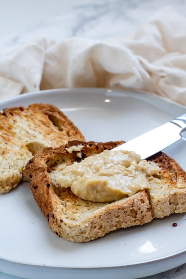 a knife spreading hummus on whole grain toast instead of mayo