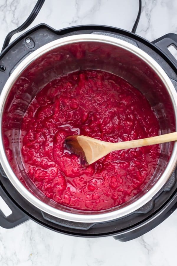 An instant pot on a marble surface full of cranberry sauce.