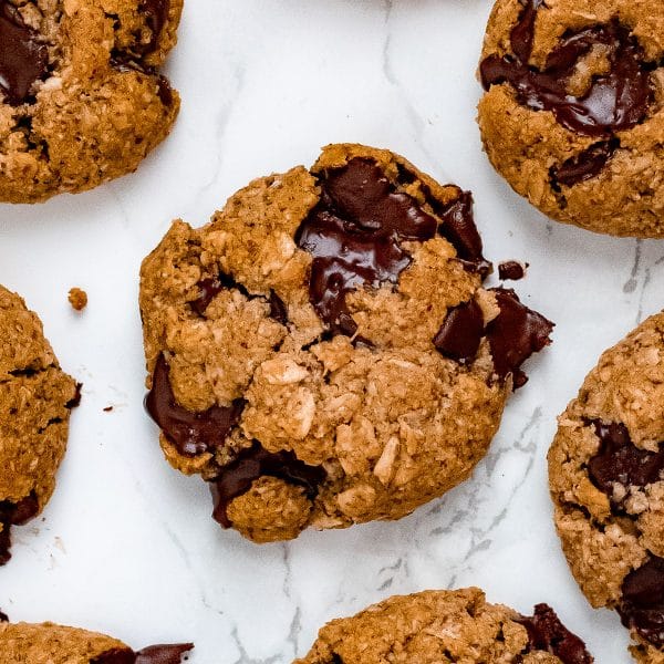 almond flour oatmeal cookies with chocolate chips on marble with one cookie broken in half