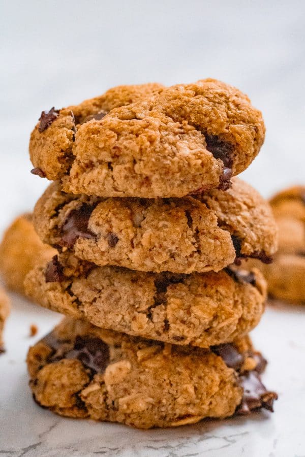 a brightly lit stack of 4 almond oat cookies with chocolate chips on marble