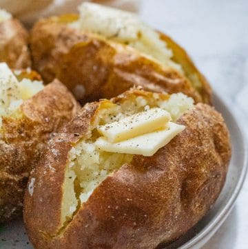baked potatoes with butter on a ceramic plate