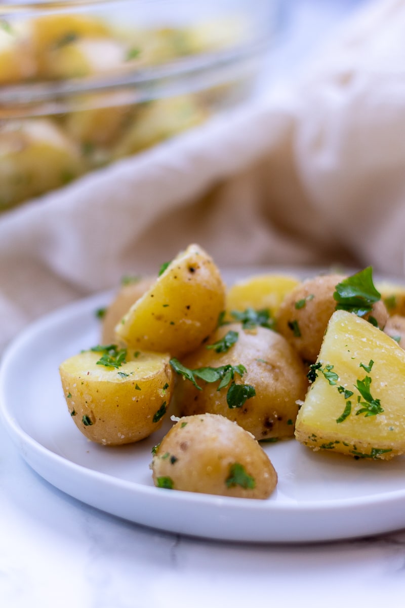 parsley and olive oil dressed baby yellow creamer potatoes on a white plate