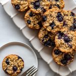 baked oatmeal cups with blueberries on a ceramic plattern with one on a small plate with a fork