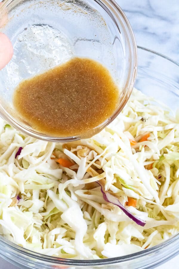 Honey lime dressing being drizzled over coleslaw vegetables for a honey lime slaw.