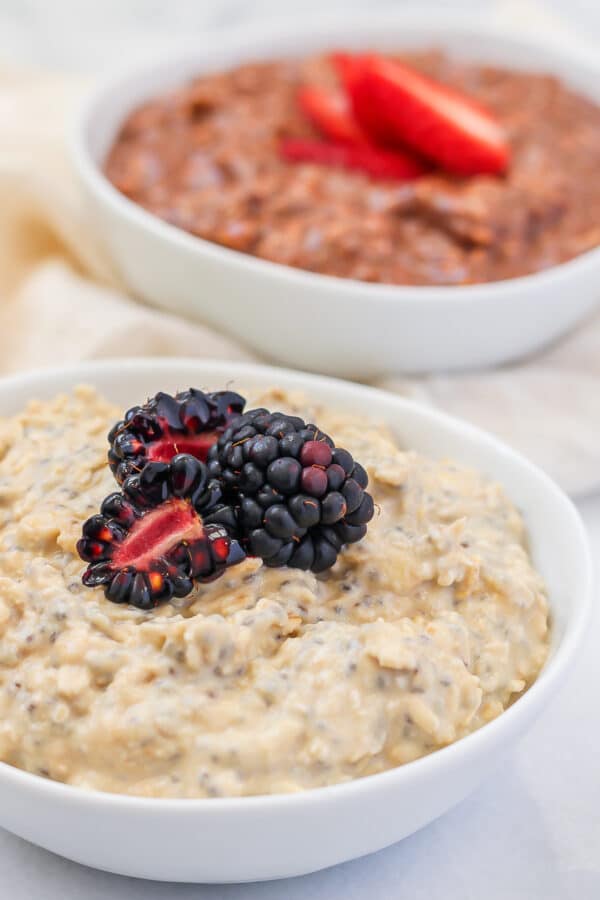 Creamy vanilla overnight oats topped with blackberries, with chocolate protein overnight oats behind them.