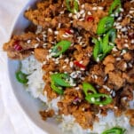 a bowl of white rice topped with saucy ground turkey, dotted with red chili flakes, green onions, and sesame seeds