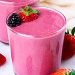 a glass of bright purple pink-colored strawberry banana blackberry smoothie