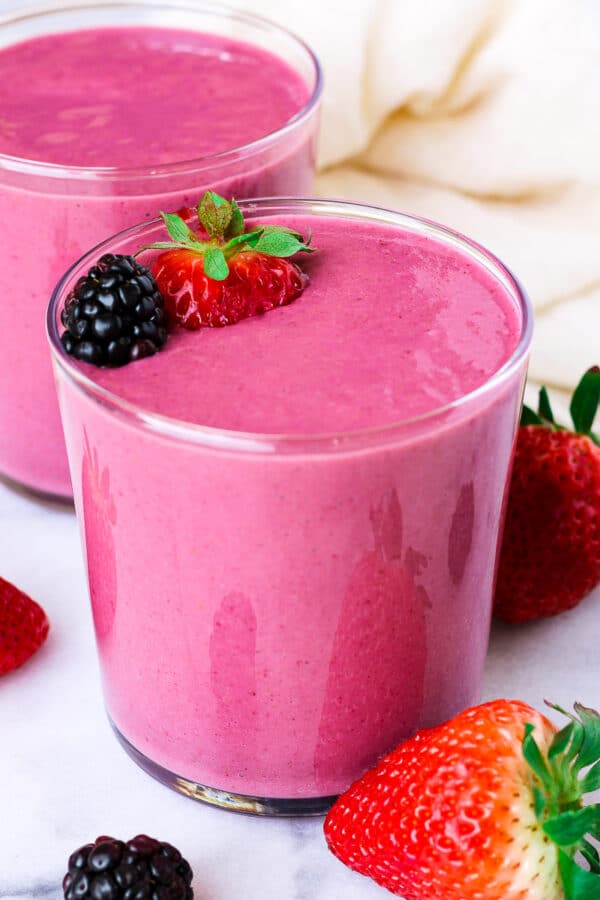 a glass of bright purple pink-colored strawberry banana blackberry smoothie