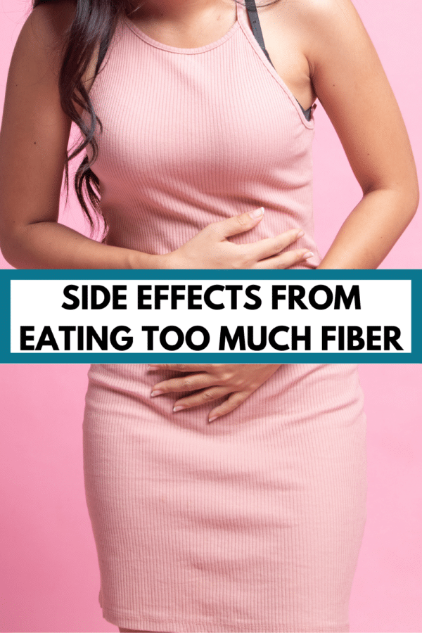 woman holding her stomach with text overlay that says "side effects from eating too much fiber"