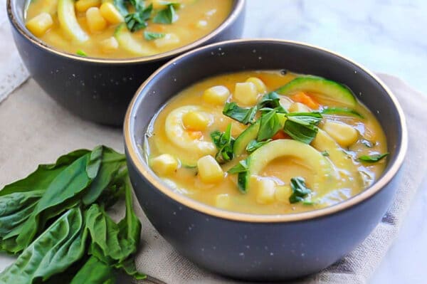 speckled charcoal bowls full of zucchini corn chowder garnished with basil