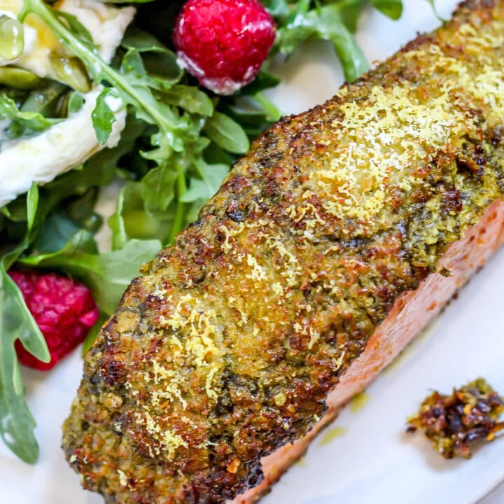 pesto crusted salmon on a white plate with salad