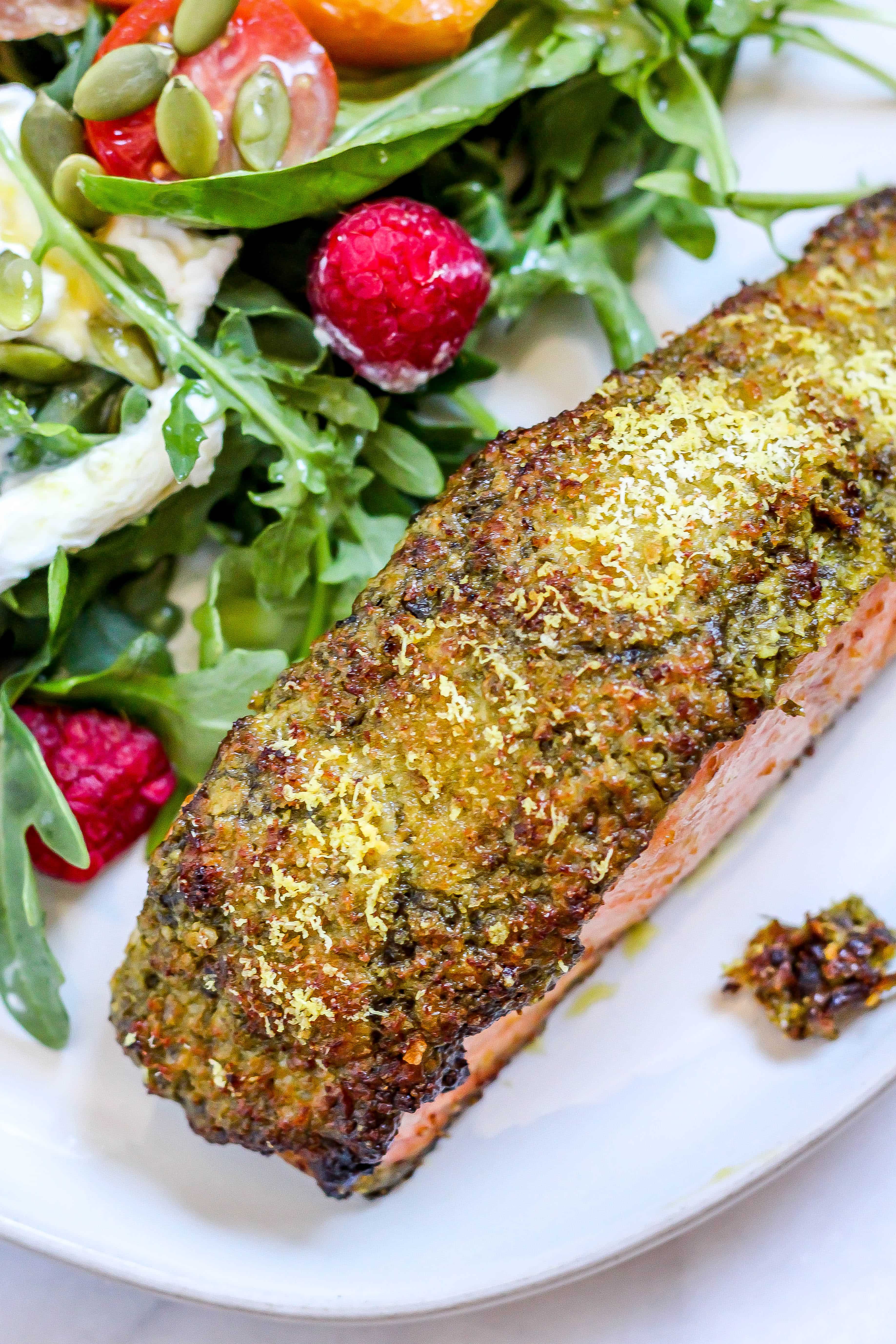 pesto crusted salmon on a white plate with salad