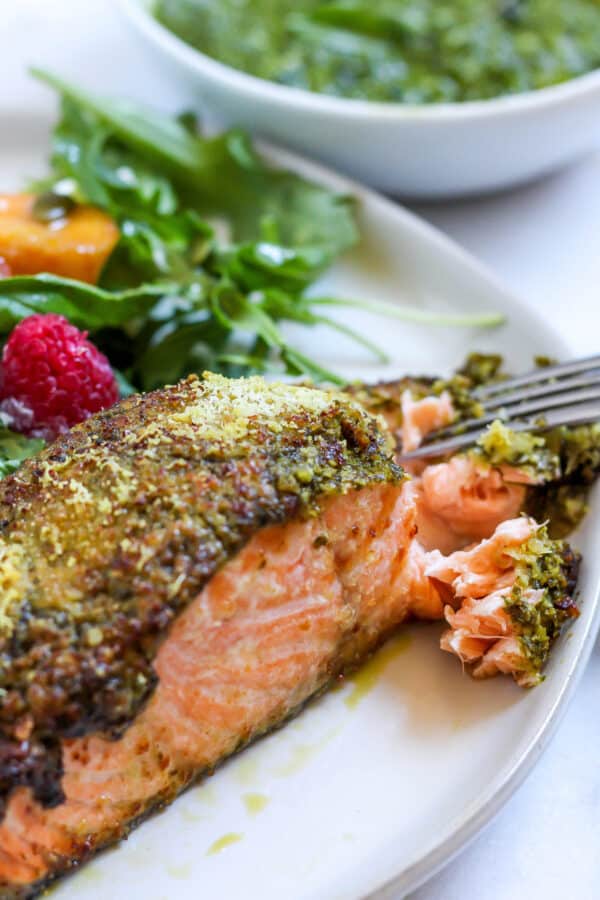 fork flaking salmon with a pesto crust