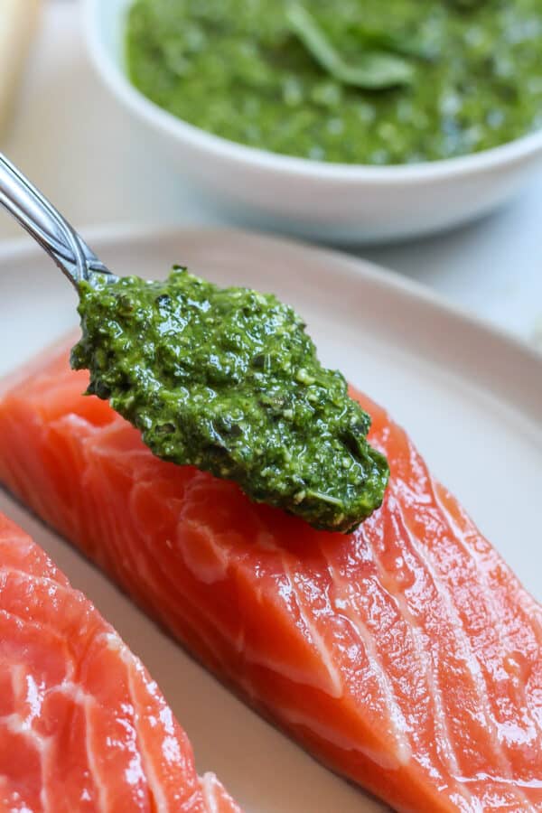 a spoonful of pesto about to be spread on salmon fillets for pesto crusted salmon