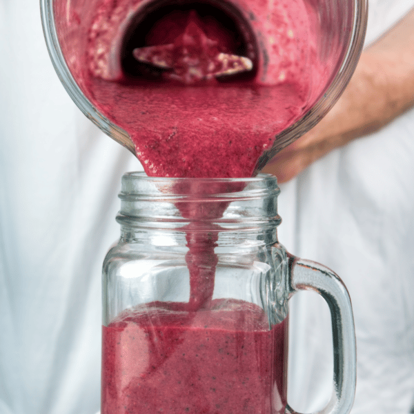 pouring a purple/red smoothie into a cup