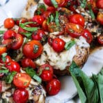 a white platter of baked bruschetta chicken